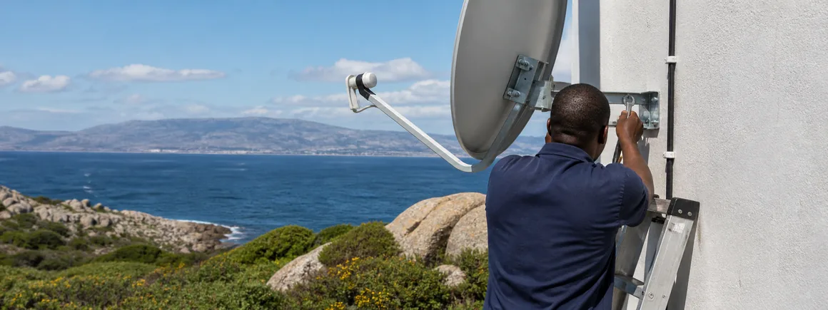 A completed satellite dish installation on a heritage stone wall above False Bay