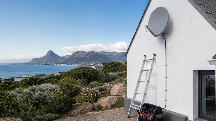 A quad LNB on a satellite dish with four dressed RG6 cable runs leaving the bracket